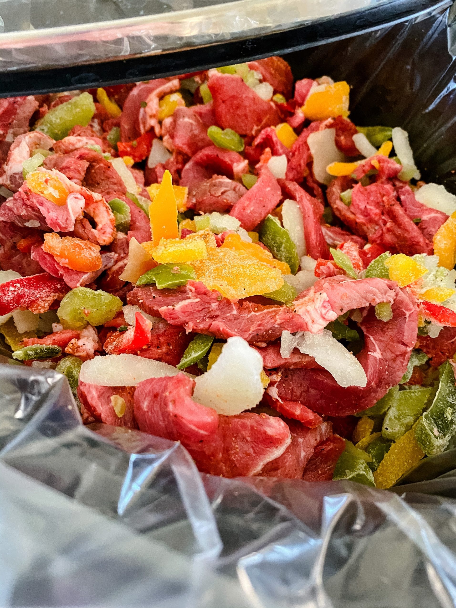 crock pot with sirloin strips and frozen peppers and onion