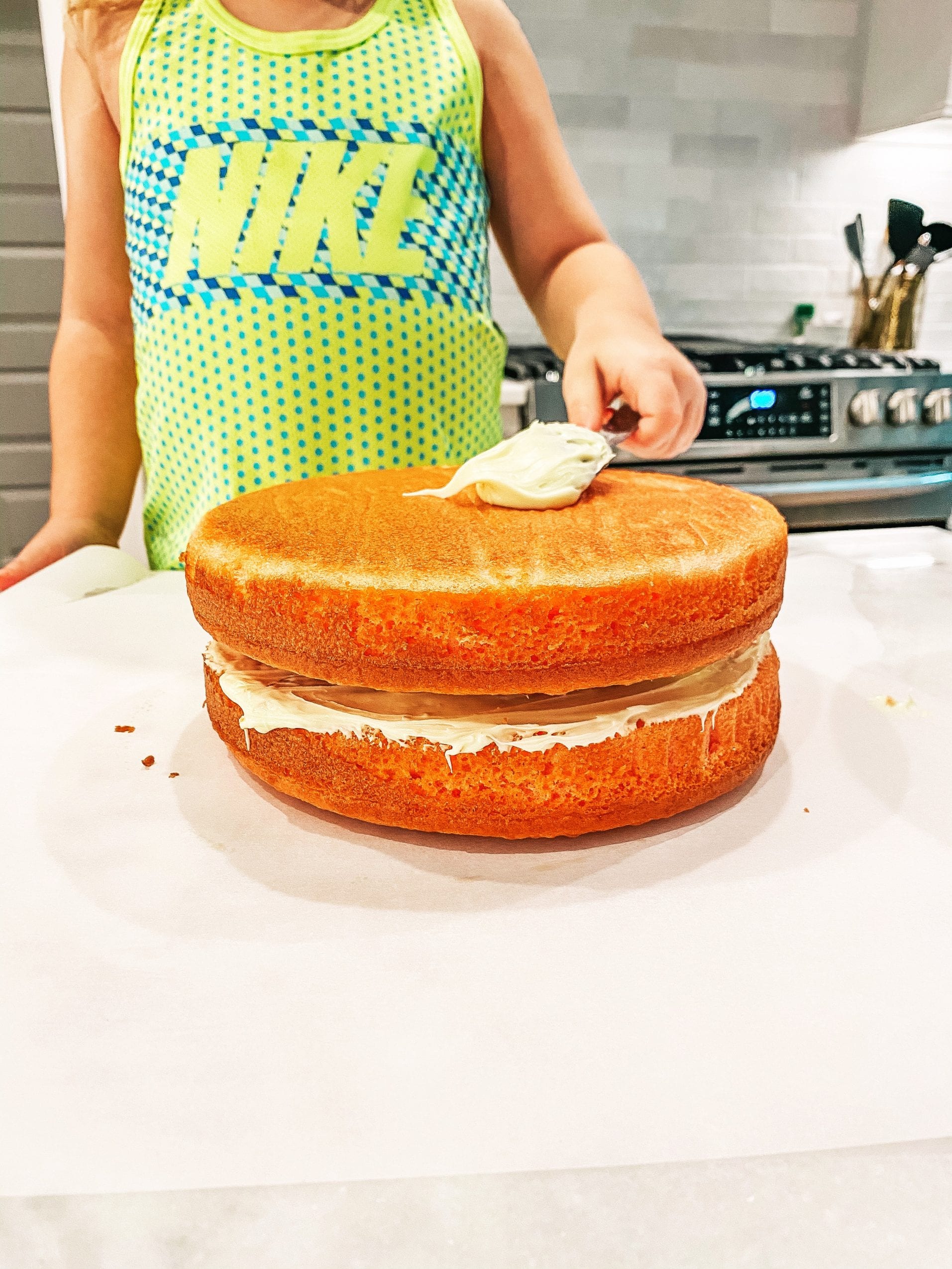 adding the frosting to the strawberry lemonade cake