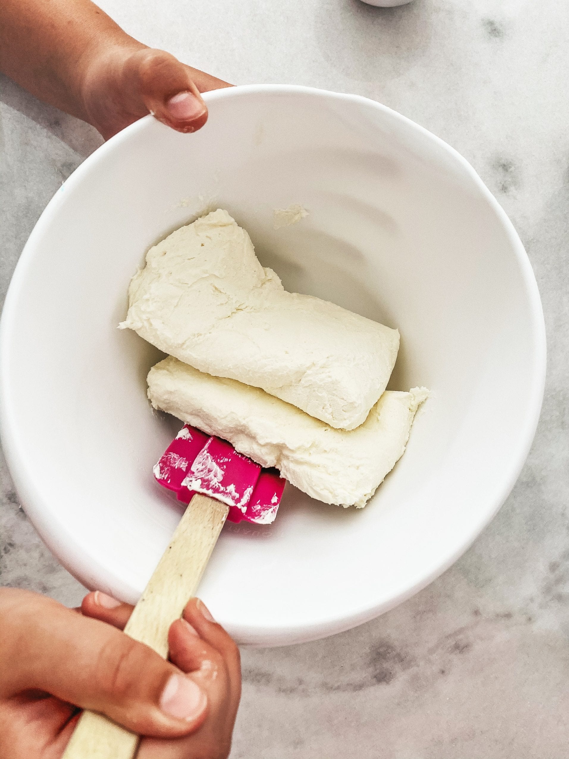 Adding softened cream cheese to a bowl