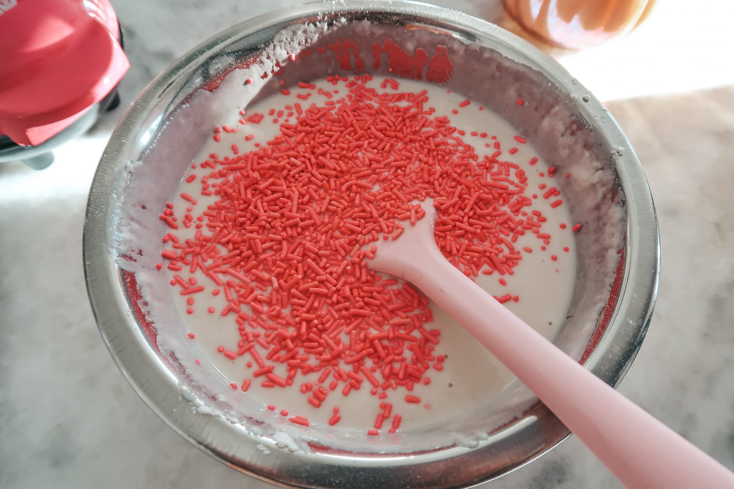 Adding the pink sprinkles to waffle batter