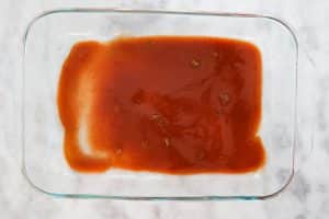 spreading down some of the enchilada sauce into baking dish