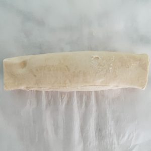 rolled pastry dough sheet filled with spinach and artichoke dip