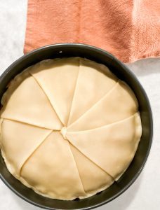 adding pie crust pieces over apple pie filling