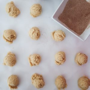 coating the snickerdoodle cookies with cinnamon and sugar