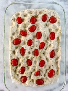 Adding cherry tomatoes to focaccia dough