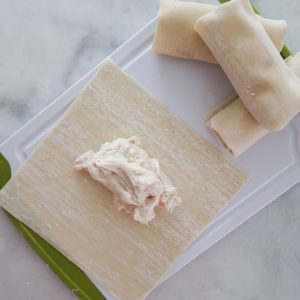 Adding the cream cheese filling to the center of an egg roll