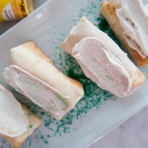 Adding the cream cheese to the top of the egg rolls
