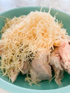 adding shredded parmesan cheese to the rotisserie chicken