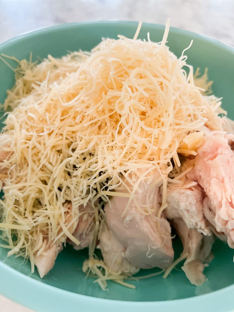 adding shredded parmesan cheese to the rotisserie chicken