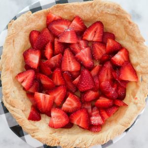 adding the sliced strawberries to the baked pie crust
