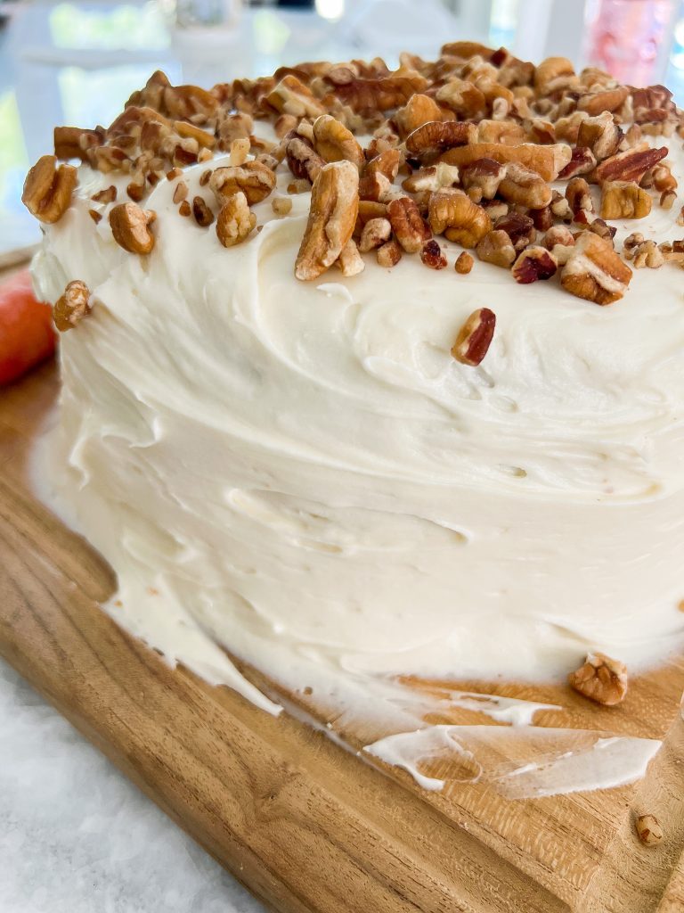 pecan pieces on top of carrot cake and cream cheese frosting