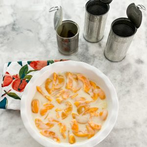 adding the condensed milk to the canned peaches